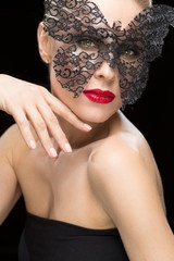 Beautiful woman in a carnival mask on black background