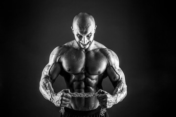 Portrait of aggressive bodybuilder trying to tear the metal chain. Isolated