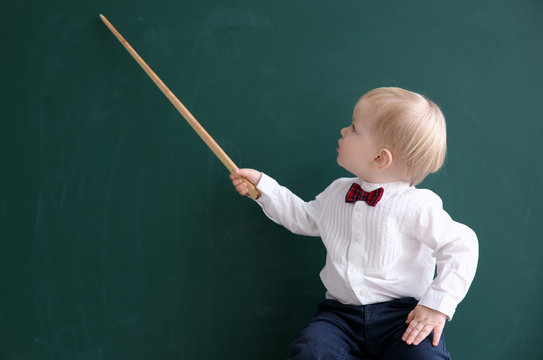 Cute little boy with pointer and blackboard on background