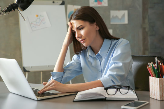Beautiful young woman suffering from headache while working in office