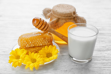 Glass of milk and golden honey on wooden table