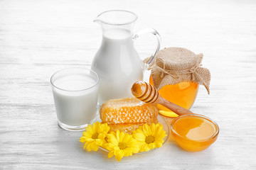 Composition of jar with milk and honey on wooden table