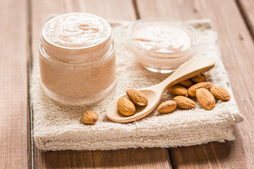 cosmetic set with almond scrub on table background