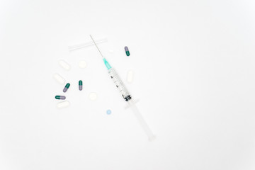 Medical syringe and pills isolated on white background