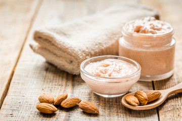 body scrub with almonds for body care on wooden table background