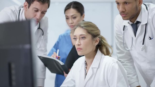  Medical team in modern hospital looking at computer & having a meeting