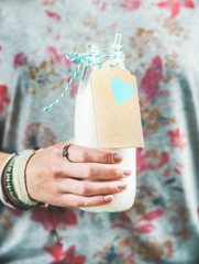 Young woman in grey t-shirt with floral pattern holding bottle of dairy-free almond milk in her hand. Clean eating, vegan, vegetarian, dieting, healthy food concept