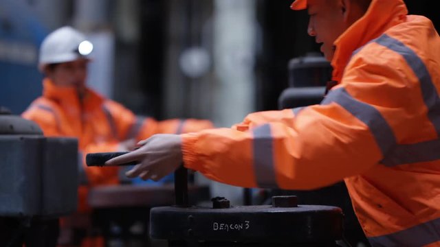  Male & female engineers in power plant turning a valve on pipeline