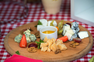 A dish with four kinds of cheese, grapes, walnuts and honey. Top view.