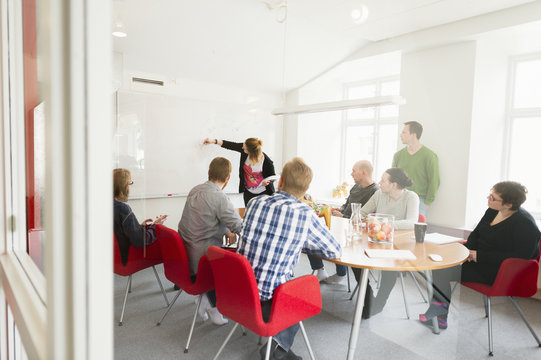 Sweden, Young woman drawing on white board during work meeting