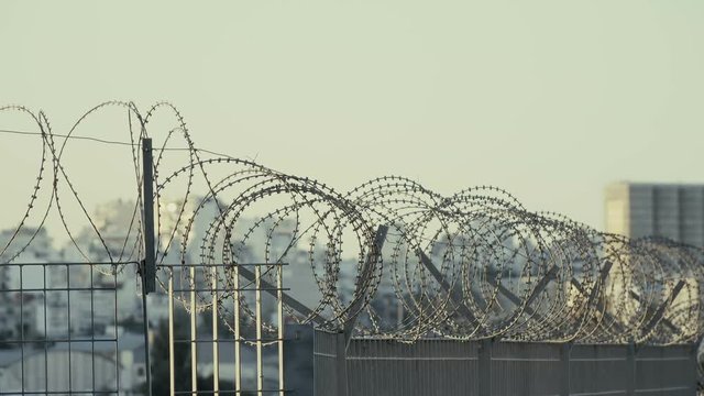 City skyline behind fence with barbed razor wire