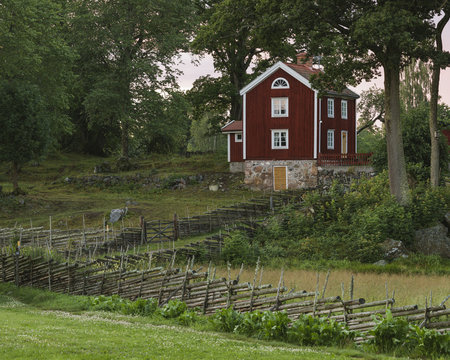 Sweden, Smaland, Stensjo, Rural scene with wooden fence and brown house