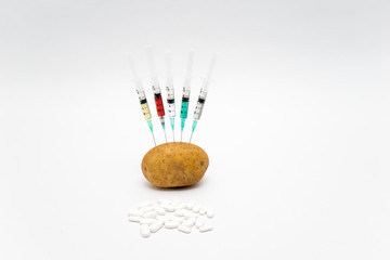 GMO concept on white background with  syringes, piils  and potato