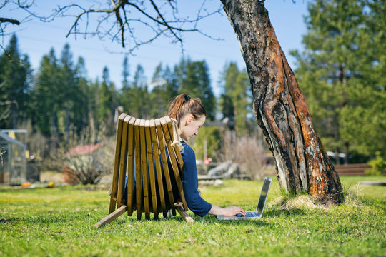 Finland, Paijat-Hame, Heinola, Mid adult woman lying down on sunlounger in garden and using laptop