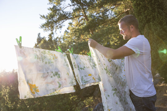 Sweden, Stockholm Archipelago, Sodermanland, Orno, Mature man hanging sheet on laundry line