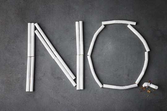 Word NO made of cigarettes on grey background