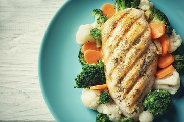 Tasty chicken breast and vegetables on plate