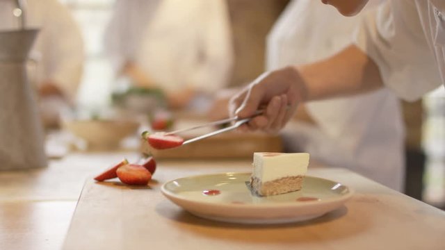  Young chef in professional kitchen gives finishing touches to dessert