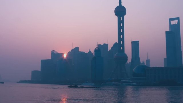 Sun in showing from behind the building in Shanghai central business district. Morning shot, sunrise. 4K UHD