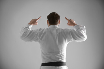 Young sporty man in kimono on light background