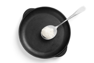 Spoon with coconut oil in frying pan on white background