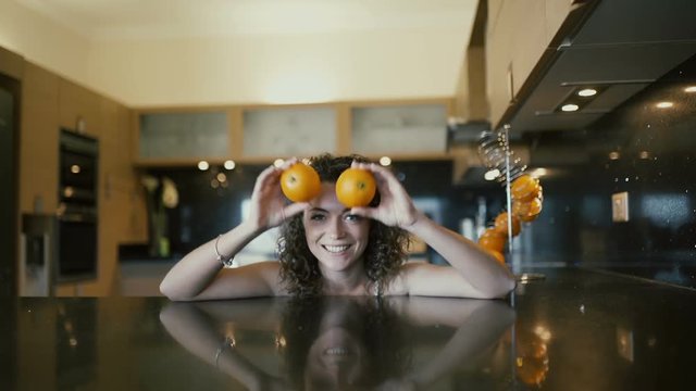 The girl laughs and fooling with oranges