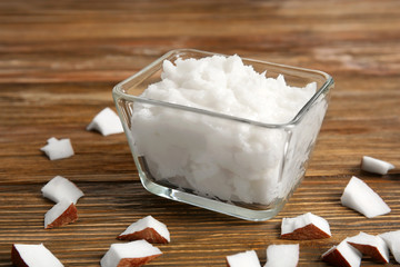 Bowl with fresh coconut oil and nut pieces on wooden background