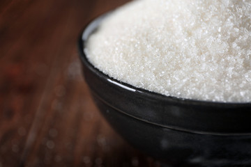 Bowl full of sugar on wooden background