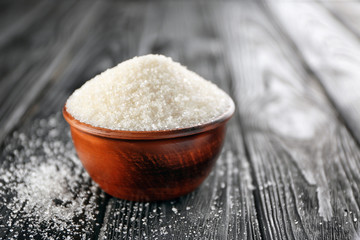 Bowl full of sugar on wooden background