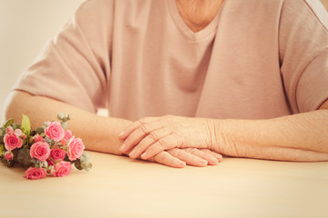 Obraz na płótnie Canvas Elderly woman with flowers at table