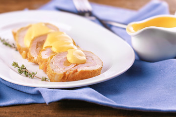 Plate with tasty chicken sliced roll on table