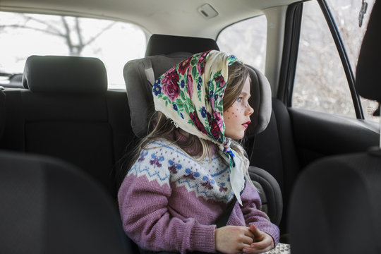 Sweden, Girl (4-5) dressed up as Easter witch sitting in car and looking through window