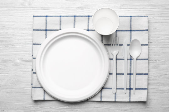 White plastic disposable tableware on wooden background