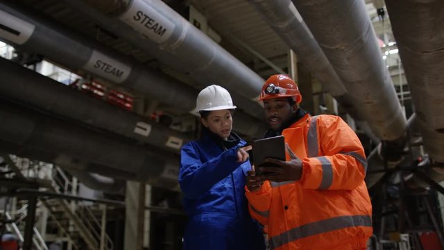  Portrait of smiling engineers in power station looking at computer tablet. 