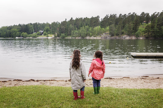 Sweden, Uppland, Roslagen, Vato, Two girls (4-5, 6-7) standing by lake shore