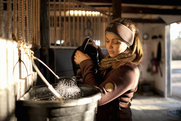 Sweden, Uppland, Faringso, Woman pouring water from watering can to bucket