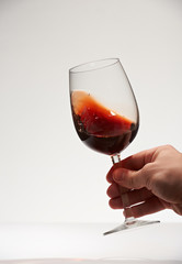 Hand shaking red wine glass