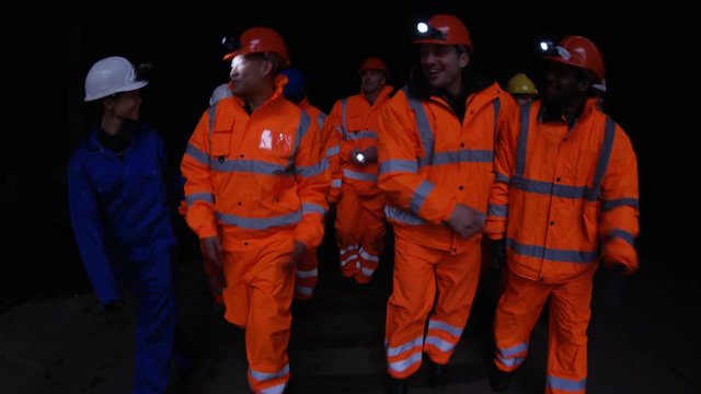  Team of workers at fuel plant come up from underground & walk into daylight