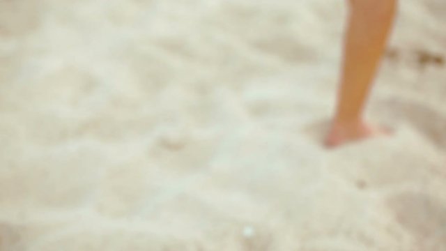 Feet and legs of Young Lady Walking on Sand along the Beach
