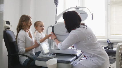 Doctor optometrist in clinic checking little girl's vision - children's ophthalmology