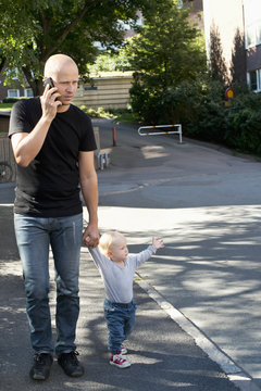 Sweden, Father and son (12-17 months) walking in city street