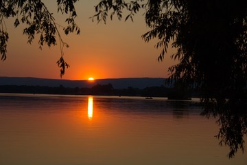 Fototapeta na wymiar Sunset Over Mountain In Front Of Lake