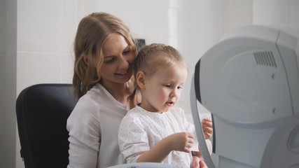 Optometrist checks child's eyesight - mother and child in ophthalmologist room