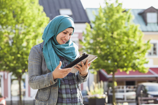 Sweden, Bleking, Solvesborg Muslim woman using tablet and smiling