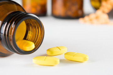 yellow tablets medicine pouring out of the bottle