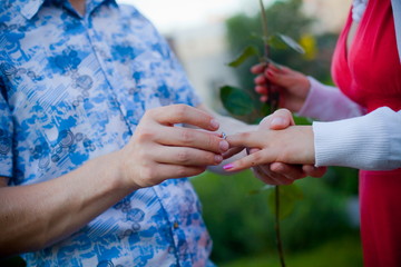 a man proposes to the woman, putting the ring on her finger