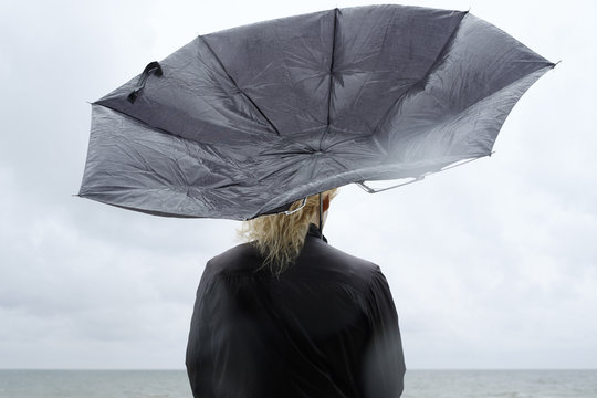 Poland, Niechorze, Woman under black umbrella watching Baltic Sea