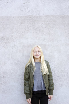 Sweden, Portrait of girl (12-13) standing against concrete wall