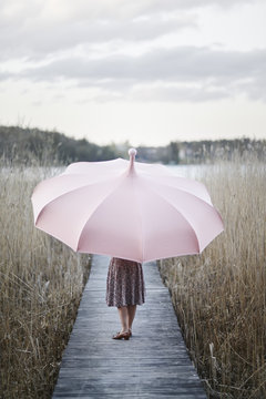 Sweden, Sodermanland, Woman with umbrella standing on wooden pier