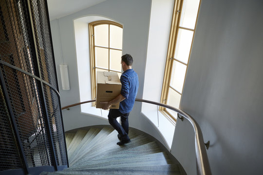Sweden, Man walking on steps, carrying box